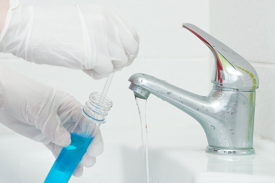 Image Of Gloved Hands Taking A Water Sample From A Bathroom Faucet